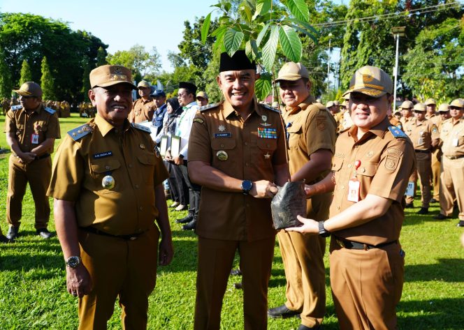 
					Ket.Bupati Tanah Laut H. Rahmat Trianto menyerahkan bibit pohon ulin secara simbolis kepada perwakilan instansi dan lembaga usai Apel Gabungan sebagai bagian dari program penghijauan dan pelestarian lingkungan.Foto.Ist
