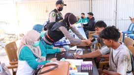 Petugas kesehatan sedang membagikan masker dan memeriksa kondisi pernapasan warga di halaman Mapolsek Bati Bati. (SANAK.ID/Dok.Humas Polres)