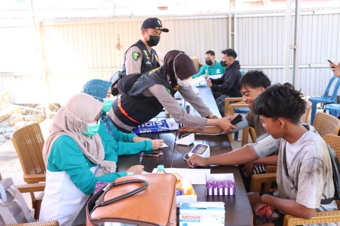 
					Petugas kesehatan sedang membagikan masker dan memeriksa kondisi pernapasan warga di halaman Mapolsek Bati Bati. (SANAK.ID/Dok.Humas Polres) 